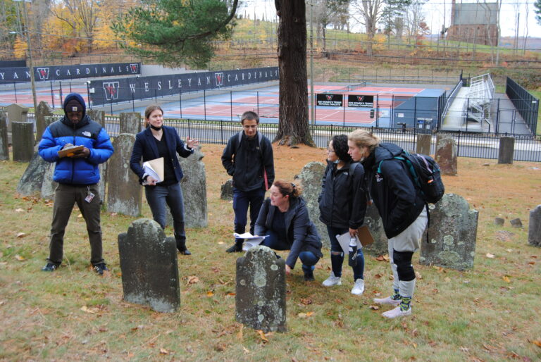 Field trip to the Washington Street Cemetery for ARCP204 Introduction to Archaeology, Fall 2021. From left to right: Mirembe McDuffie-Thurmond (‘25), Katherine Brunson, Rijs Johansongordet (‘24), Elle Bixby (‘23), Angela Rojas-Merchan (‘24), and Juliette Vemmer (‘25); Photo by Kiran Kowalski (‘23).