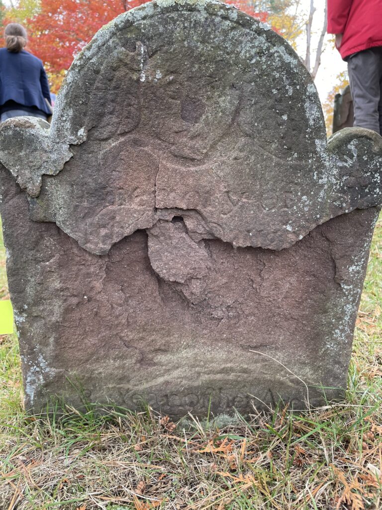 Heavily eroded gravestone. The full inscription is no longer visible, but students in ARCP 204 Intro to Archaeology used remaining clues from the partial inscription, the gravestone decoration, and carving style to guess that this grave dates to between 1775 and 1780. Photo by Efi Miller (‘25).